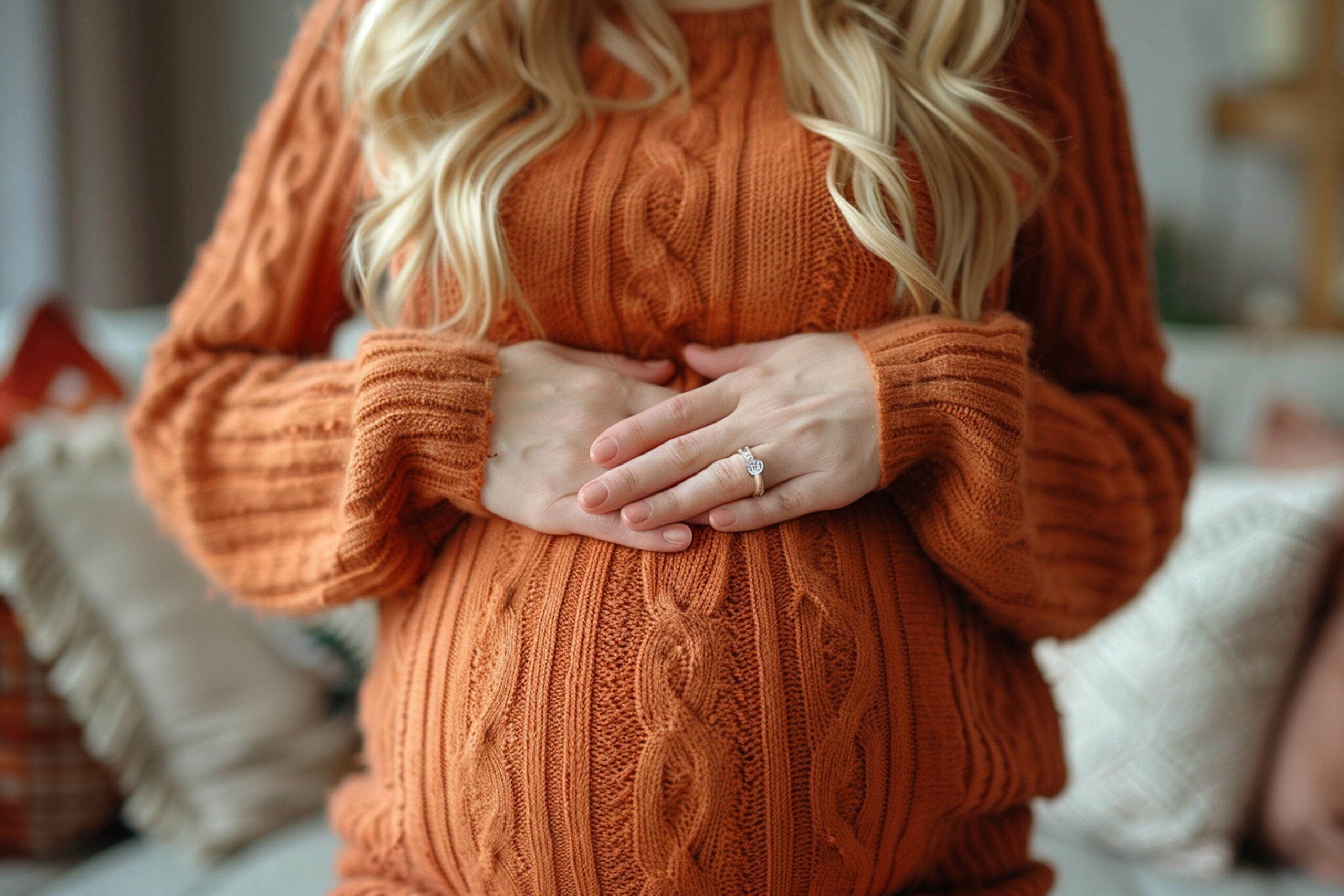 Pregnant woman in orange sweater holding belly showing prenatal care Salinas